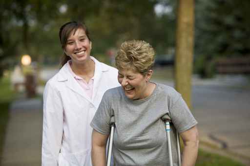 Woman with crutches stands in front of caregiver