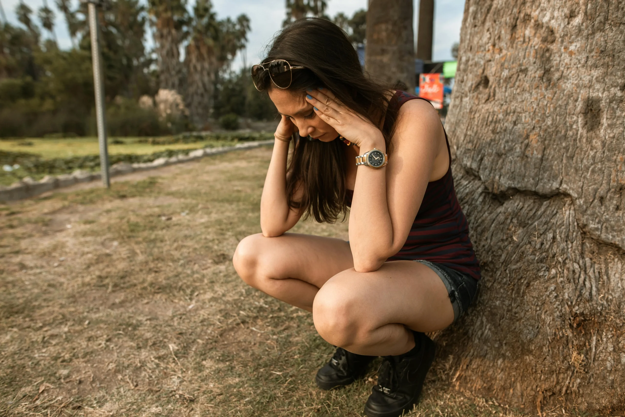 girl stressed sitting next to tree