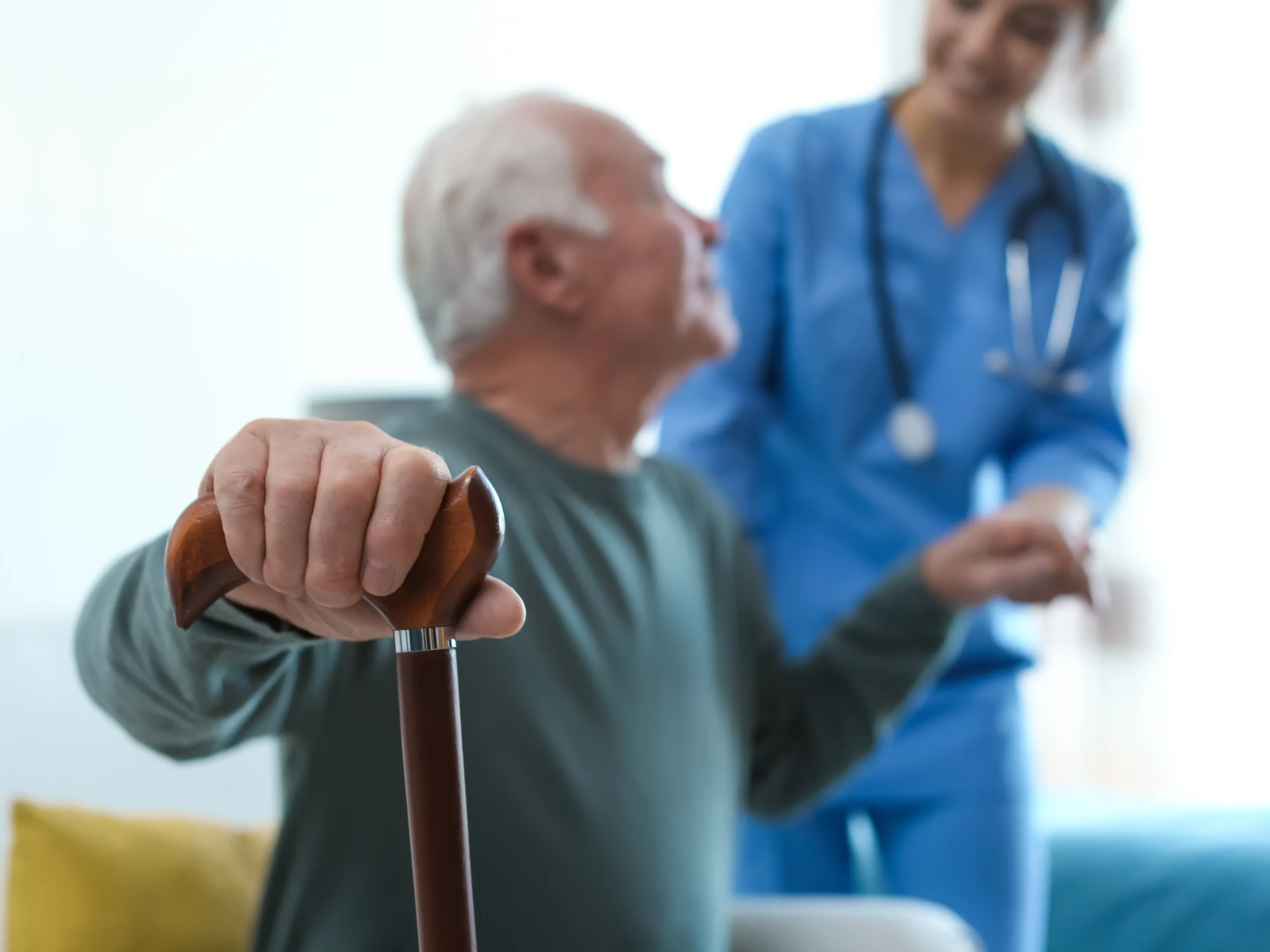 elderly man using cane and nurse to assist in standing up